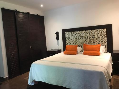 a bedroom with a bed with two orange pillows on it at COTTON HOUSE DE LABRADOR in Labrador