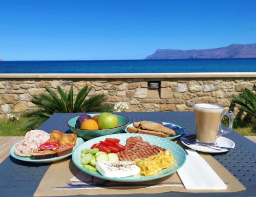 a table with plates of food and a cup of coffee at Captain's Beach Apartments in Kissamos