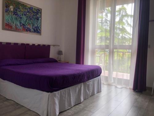 ein Schlafzimmer mit einem lila Bett und einem Fenster in der Unterkunft Casa Simonetta in Foligno