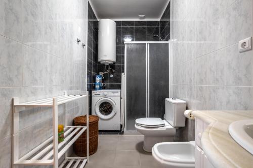 a bathroom with a toilet and a washing machine at Beach House Vista Mar - Praia do Pedrógão in Coimbrão
