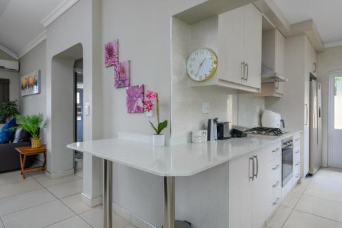 a kitchen with a white counter and a clock on the wall at Villa Caylee Caribbean Estates - Ultra-Luxurious - Rimas Interiors Designs - Private Beachfront Escape - Premium serviced for 8 Guests in Port Edward