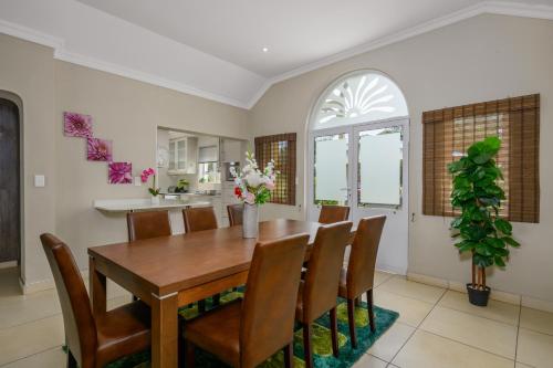 a dining room with a wooden table and chairs at Villa Caylee Caribbean Estates - Ultra-Luxurious - Rimas Interiors Designs - Private Beachfront Escape - Premium serviced for 8 Guests in Port Edward