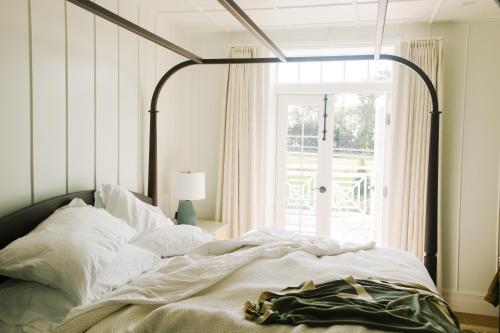 1 dormitorio con 1 cama grande y ventana grande en Canoe Place Inn & Cottages en Hampton Bays