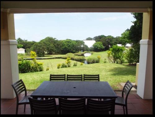 une table noire avec des chaises et une vue sur un champ dans l'établissement Caribbean Estates Villa Caylee - Ultra-Luxurious - Rimas Interiors Designs - Private Beachfront Escape - Premium serviced for 8 Guests, à Port Edward