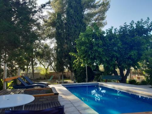 a swimming pool with a table and chairs next to it at Casas de Campo Los Corralitos in Mendoza