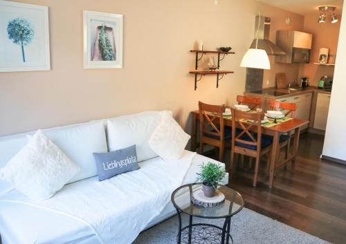 a living room and kitchen with a white couch and a table at Apartment Caroline - Gemütliche Ferienwohnung mit Pool, Sauna und Hochschwarzwaldcard in Schluchsee