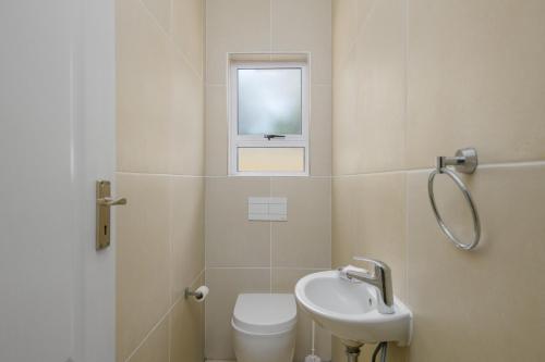 a bathroom with a sink and a toilet and a window at Villa Caylee Caribbean Estates - Ultra-Luxurious - Rimas Interiors Designs - Private Beachfront Escape - Premium serviced for 8 Guests in Port Edward