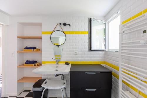 une salle de bain avec un lavabo et un miroir dans l'établissement Maison Royan Foncillon-Chay classée PMR, à Royan