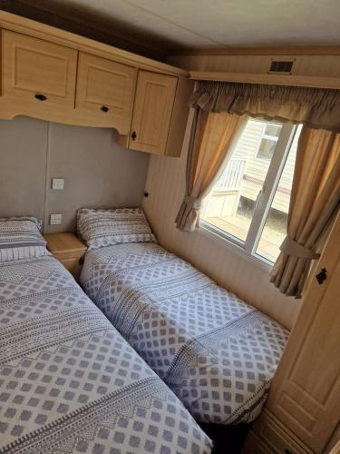 two beds in an rv with a window at Elegance on Highfields F28 in Lincolnshire