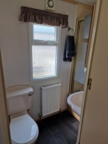 a bathroom with a toilet and a window and a sink at Elegance on Highfields F28 in Lincolnshire