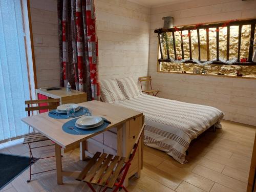 um pequeno quarto com uma cama, uma mesa e cadeiras em Les Gîtes de LAURES em Monblanc