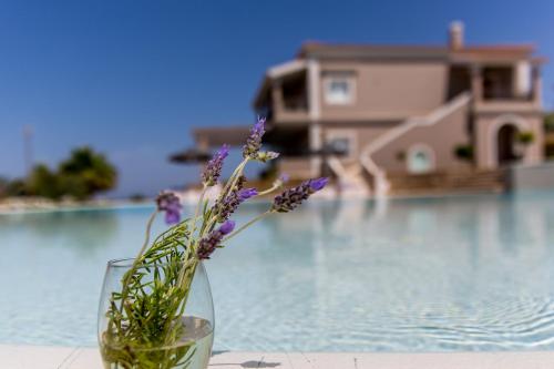 a glass vase with flowers in it next to a pool at Pictures Suites in Agios Stefanos