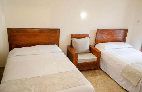 a room with two beds and a chair in it at Hotel Catedral in Cuernavaca