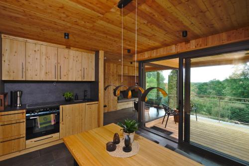 a kitchen with wooden cabinets and a dining table with a view of a deck at Baumwipfel-Resort "Lug ins Land" in Ilsenburg