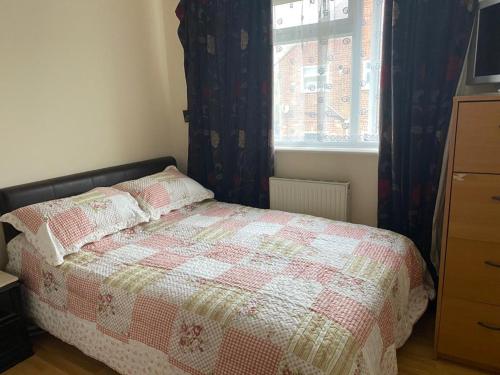 a bedroom with a bed with a quilt and a window at Specious Room in Northolt in Northolt