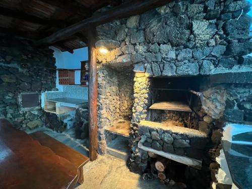 a stone fireplace in a room with a wooden table at Vivienda Vacacional Tanganasoga in Frontera