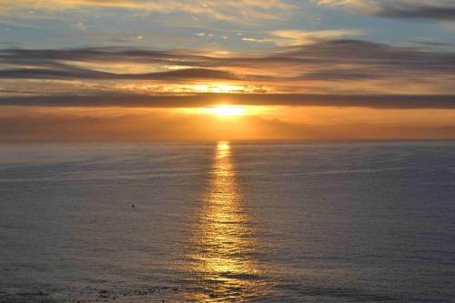 a sunset over the ocean with the sun setting at Moonglow Guesthouse in Simonʼs Town