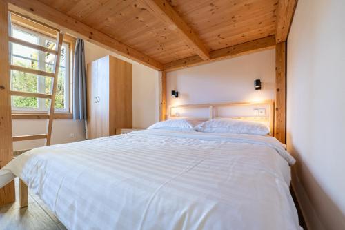 a bedroom with a large white bed with a wooden ceiling at Apartmány Pod Kolonádou in Janske Lazne