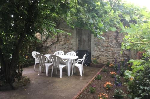 una mesa blanca y sillas en un jardín en Chambres d'Hotes dans les Gorges de la Sioule en Chouvigny