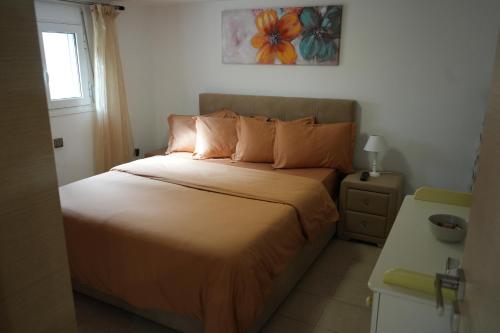 sypialnia z łóżkiem z pomarańczową pościelą i oknem w obiekcie Cozy apartment near sea and airport w mieście Artemida