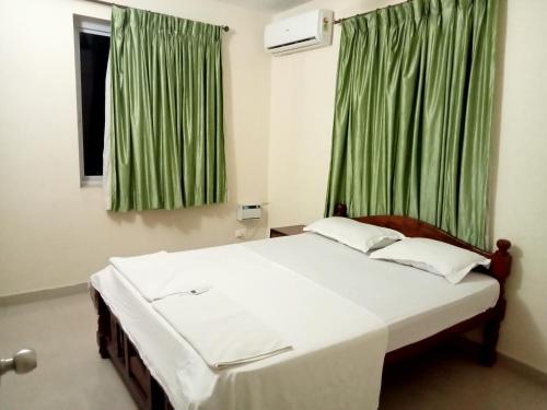 a bedroom with a large bed with green curtains at Asian Paradise comfort in Varca