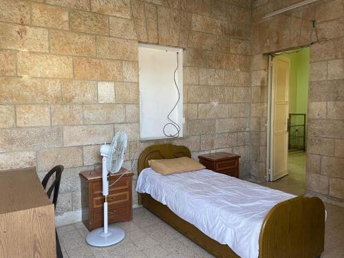 1 dormitorio con cama y pared de ladrillo en Bayt Ateeq (Ateeq's house), en Bethlehem