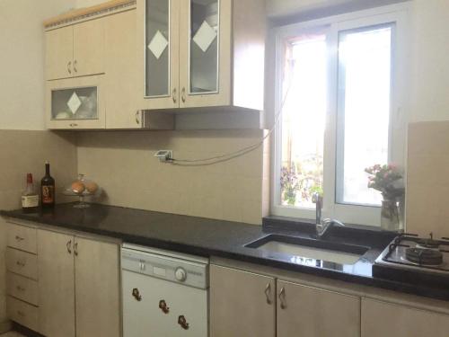 cocina con armarios blancos, fregadero y ventana en Bayt Ateeq (Ateeq's house) en Bethlehem