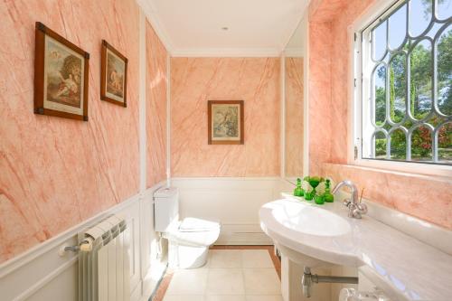 ein Bad mit einem WC, einem Waschbecken und einem Fenster in der Unterkunft Villa at Quinta do Perú Golf and Country Club in Quinta do Conde
