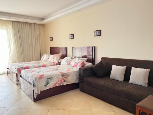 Cecelia resort في الغردقة: غرفة معيشة بها سريرين وأريكة