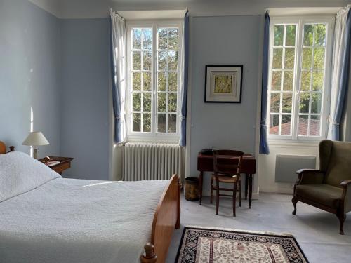 una camera da letto con un letto, una sedia e finestre di Le Pré aux Moines a Fontcouverte