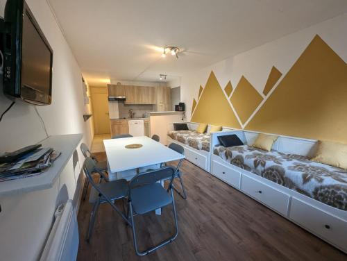 Cette petite chambre comprend deux lits, une table et des chaises. dans l'établissement Studio 1 pièces avec balcon pieds des pistes la mongie tourmalet, à Bagnères-de-Bigorre