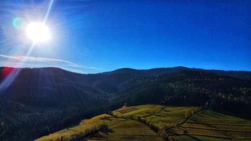 a sun is shining over a mountain with trees at Domki na Widoku in Lubomierz