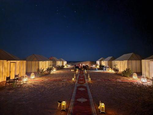 Une rangée de tentes dans un désert la nuit dans l'établissement Ahlam Luxury Camp, à Merzouga