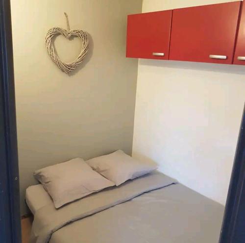 een kleine kamer met een bed met een hart aan de muur bij Superbe studio dans la vallée de l'Eau d'Olle. in Allemont