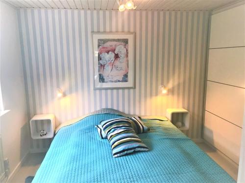 a bedroom with a blue bed with striped walls at Dejlig feriebolig med havudsigt i naturskønt område in Munkebo