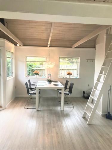 a dining room with a white table and chairs at Skøn feriebolig med havudsigt i naturskønt område in Munkebo