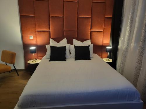 a bedroom with a large white bed with black pillows at Cosy Corner - Appartement spa - Jacuzzi in Marsannay-la-Côte