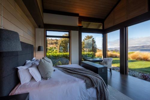 a bedroom with a large bed and large windows at Lodge Lorien in Glenorchy