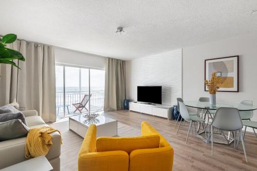 a living room with a yellow couch and a table at Oceanfront Beach House, Satellite Beach in Satellite Beach