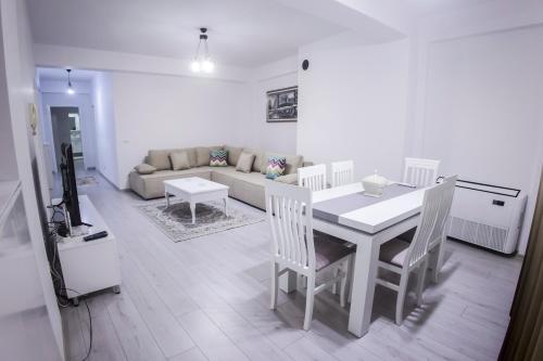 een woonkamer met een tafel en stoelen en een bank bij GRANDE APARTMENT KORCE in Korçë