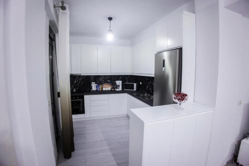 a kitchen with white cabinets and a stainless steel refrigerator at GRANDE APARTMENT KORCE in Korçë
