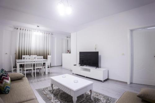 ein Wohnzimmer mit einem Sofa, einem TV und einem Tisch in der Unterkunft GRANDE APARTMENT KORCE in Korçë