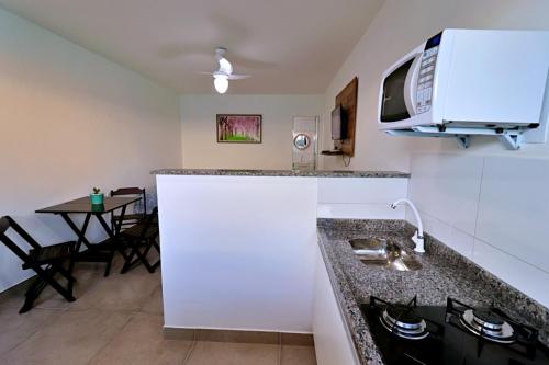 cocina con fregadero, microondas y mesa en Búzios Conforto Guest House - 450 metros Rua das Pedras, en Búzios