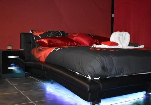 un letto nero con cuscini rossi in una stanza di L’Escale du Donon « Le Temple de Cupidon » a Grandfontaine