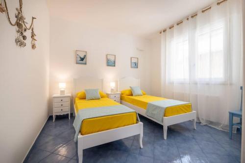 two beds in a white room with a window at Belvedere Apartments B in Marina di Mancaversa