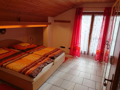 a bedroom with a large bed with red curtains at Haus-Brecherspitzblick in Schliersee