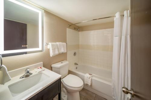 a bathroom with a toilet and a sink and a tub at Baymont by Wyndham Laredo in Laredo