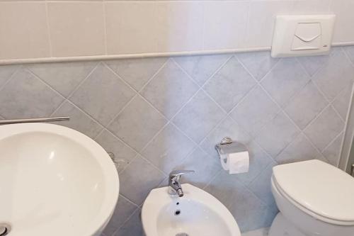 Łazienka z białą toaletą i dozownikiem papieru toaletowego w obiekcie Villa Fronte Mare w mieście Stintino