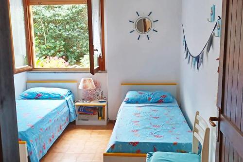 dwa łóżka w pokoju z oknem w obiekcie Villa Fronte Mare w mieście Stintino