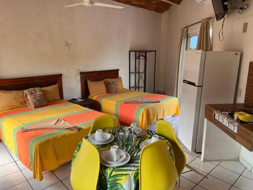 a room with two beds and a table and chairs at MonteMar Hotel y Bungalows in Rincon de Guayabitos